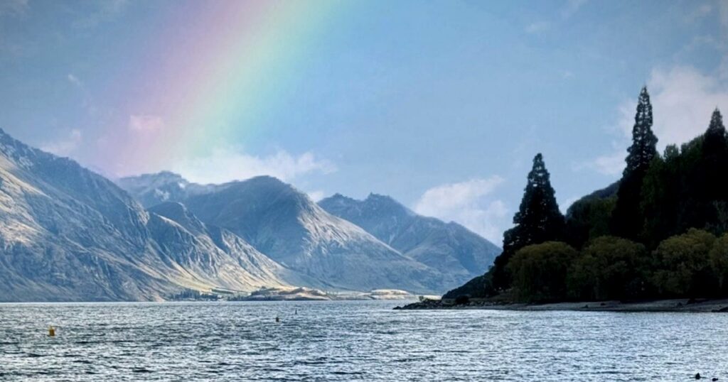 A rainbow arching over a calm lake after rain