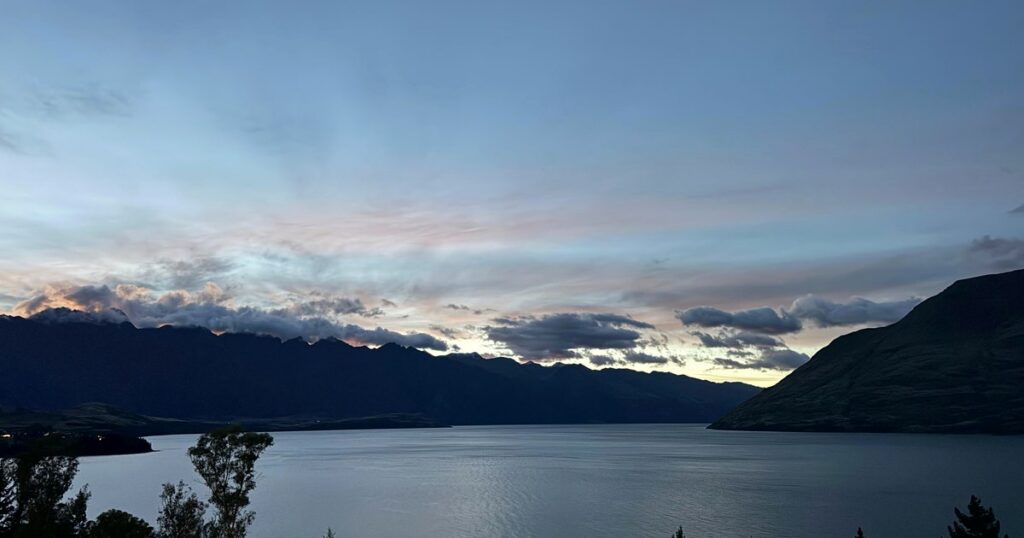 A still lake reflecting distant mountains under soft light