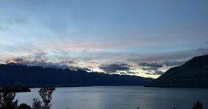 A still lake reflecting distant mountains under soft light