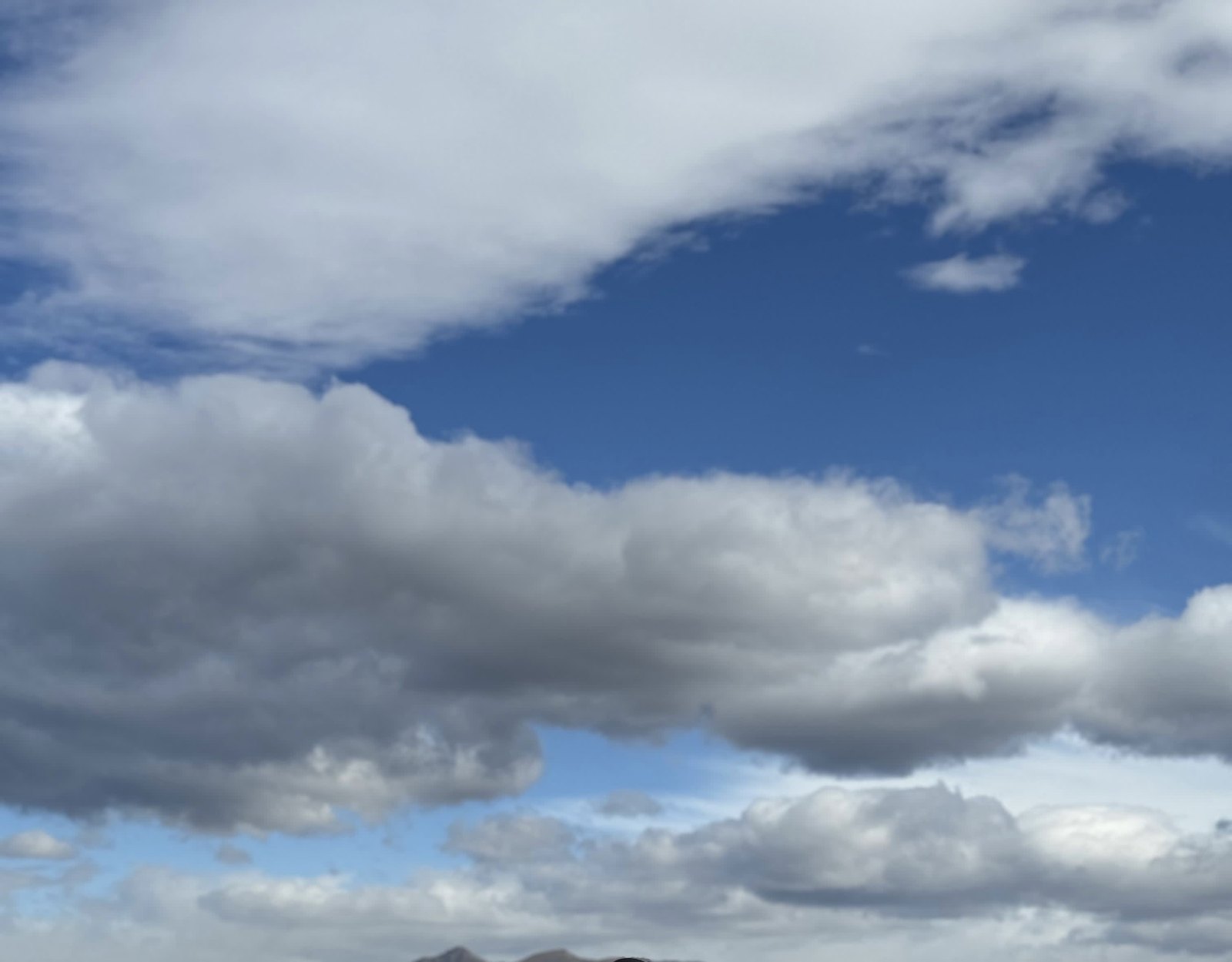 White and grey clouds drifting across a deep blue sky